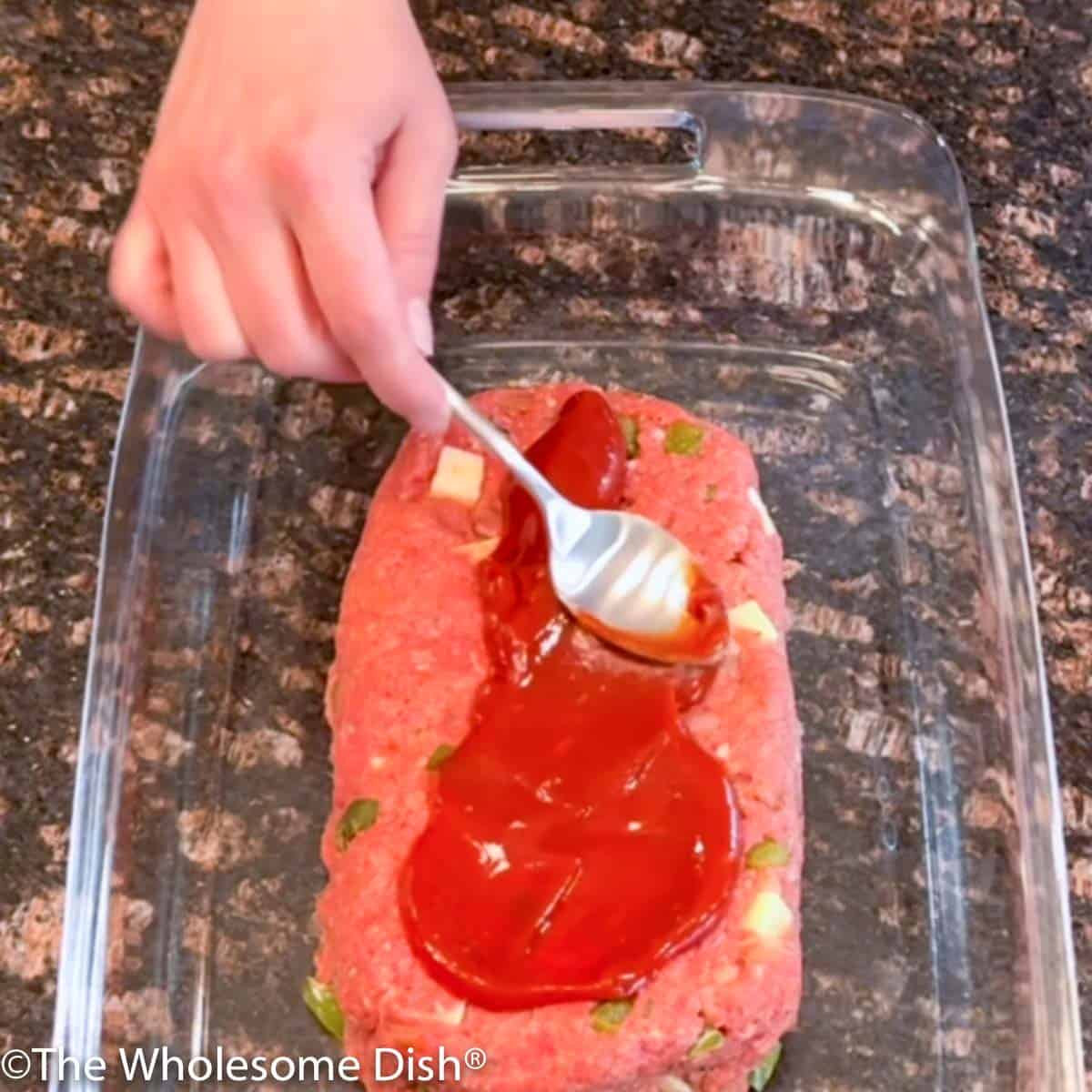 Spreading ketchup on an uncooked meatloaf.