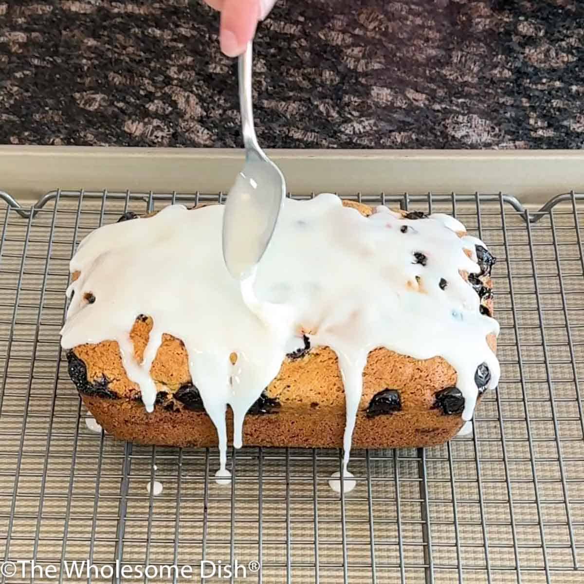 Spreading lemon glaze on top of lemon blueberry bread.