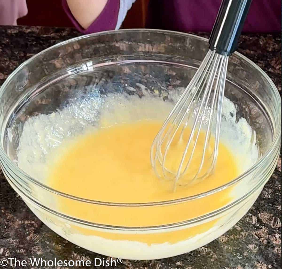 A glass mixing bowl full of the liquid ingredients for lemon blueberry loaf.