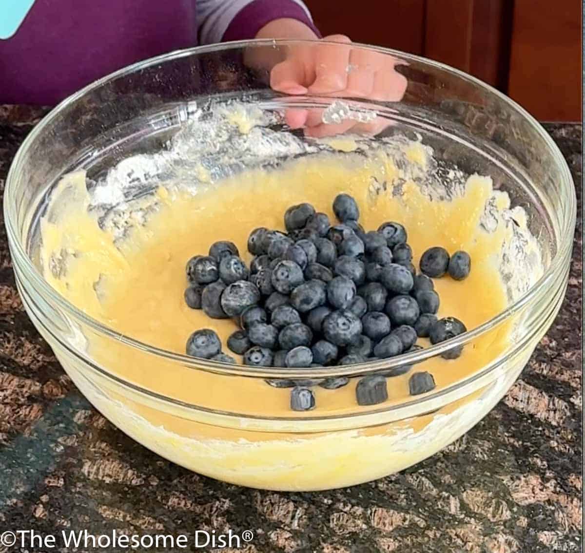 Adding blueberries to the batter.