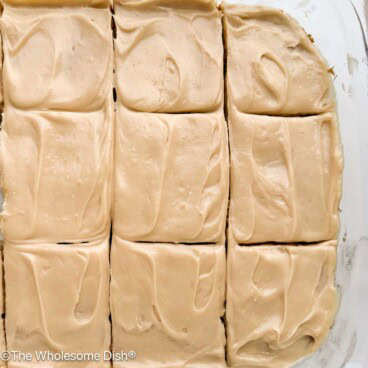 Sliced apple blondies with maple cream cheese frosting in a baking dish.