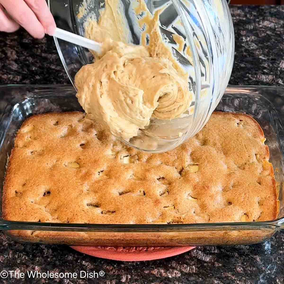 Topping the apple blondies with the frosting.