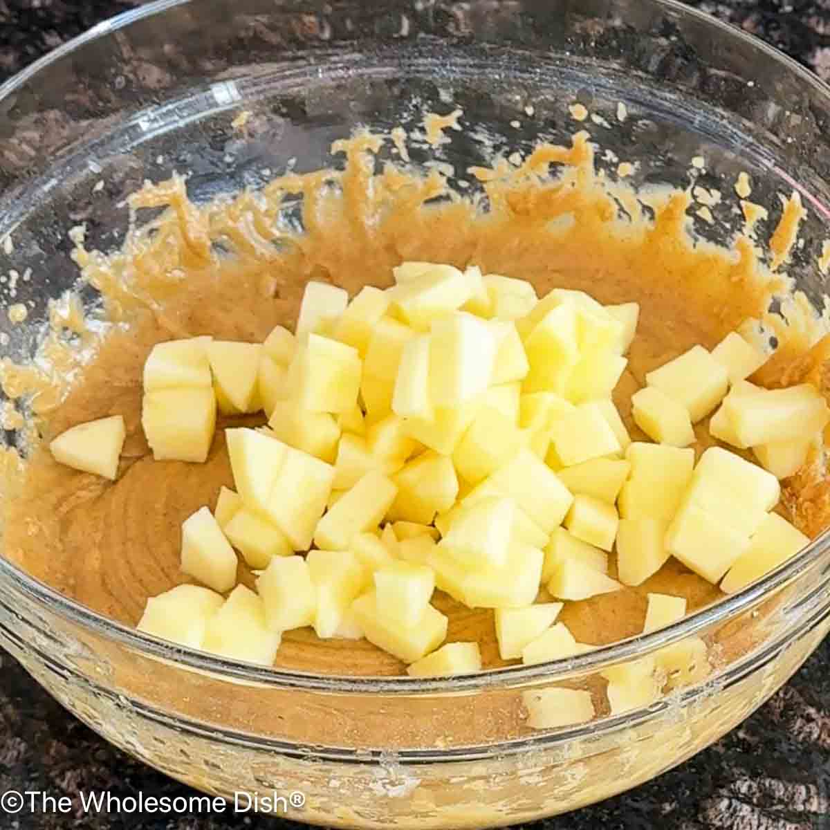 Adding peeled chopped apples to the bowl.