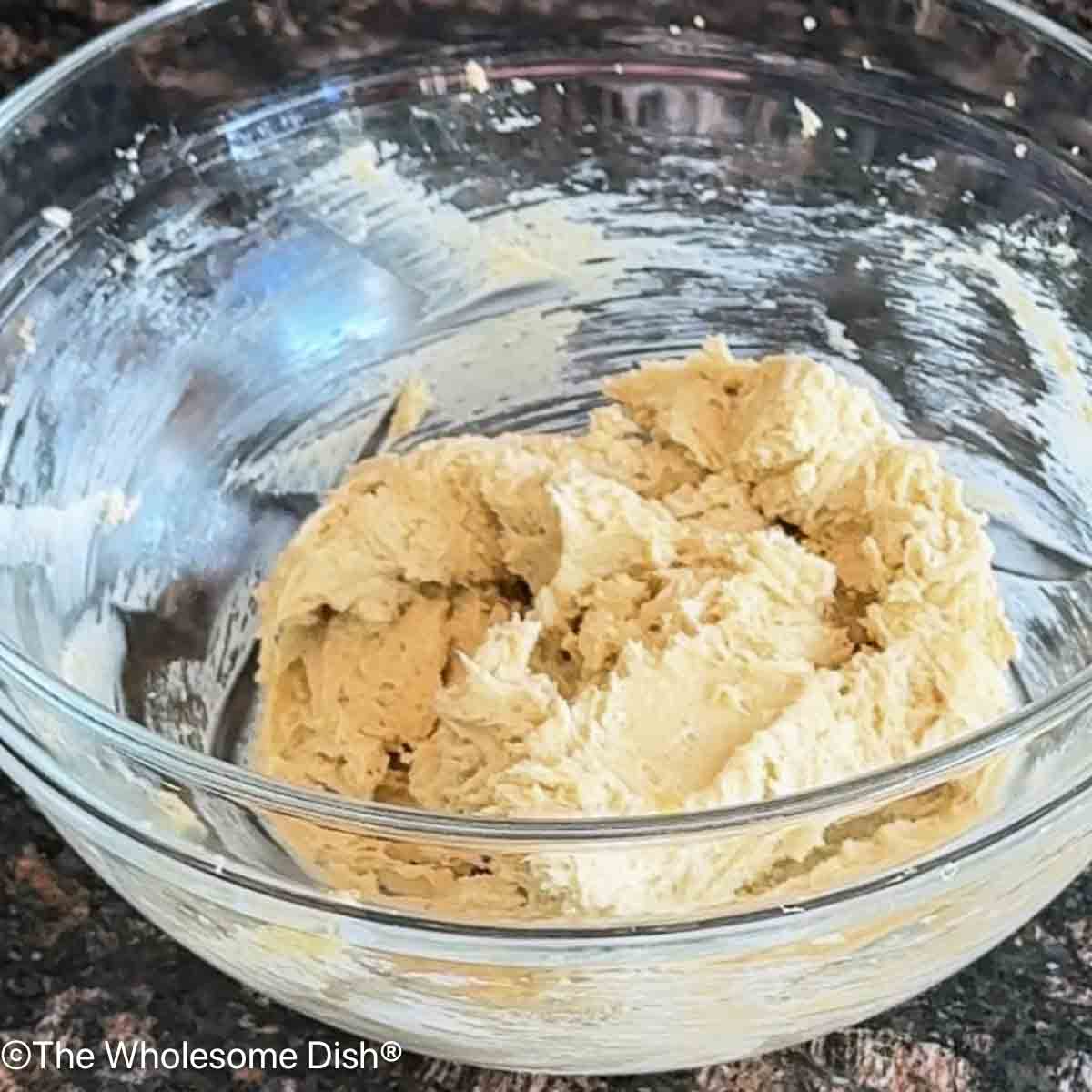 Cream cheese, brown sugar, and maple syrup mixed together in a glass bowl.