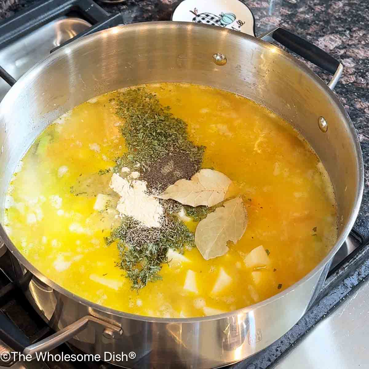 Adding parsley, salt, pepper, garlic powder, thyme, and dried bay leaves to the pot.