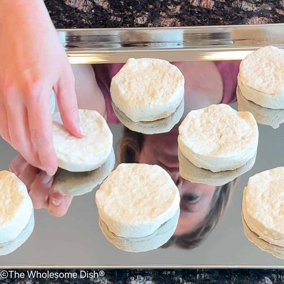 Placing refrigerated biscuit dough onto a baking sheet.