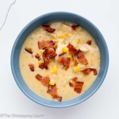 Blue bowl filled with chicken bacon ranch corn chowder topped with crumbled bacon.