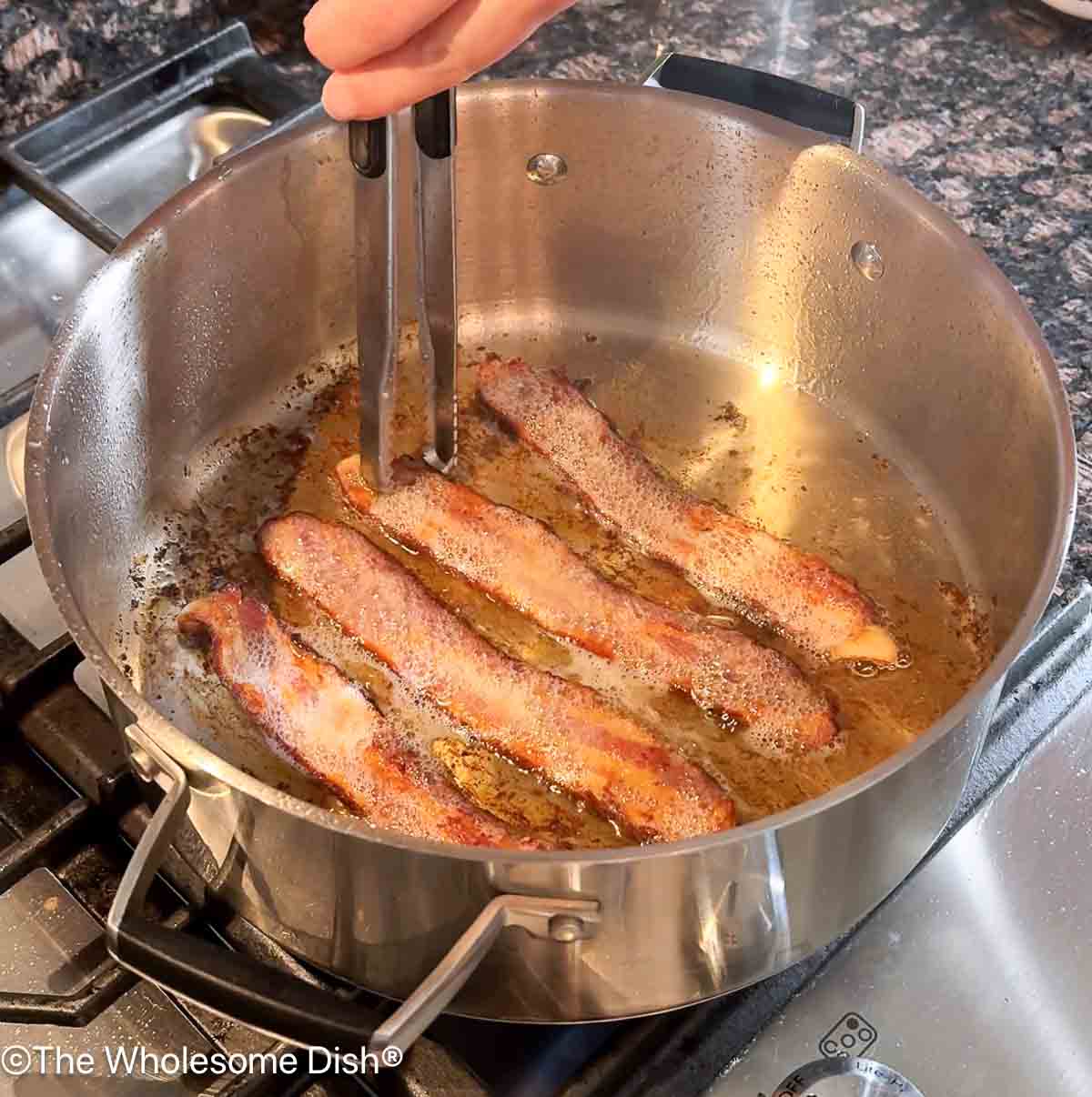 Sliced bacon cooking in a pot.