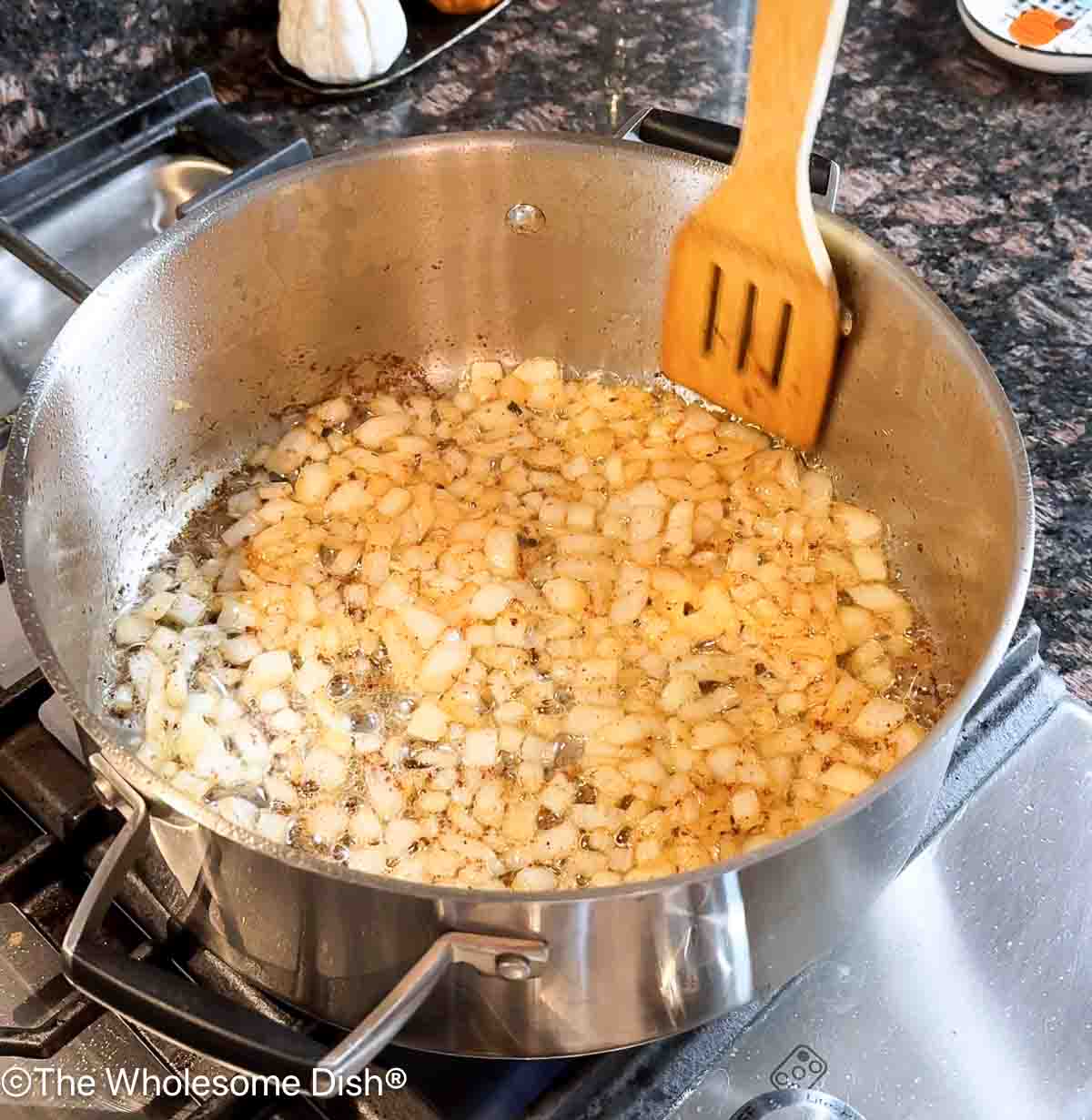 Chopped onions cooking in a pot with bacon grease.