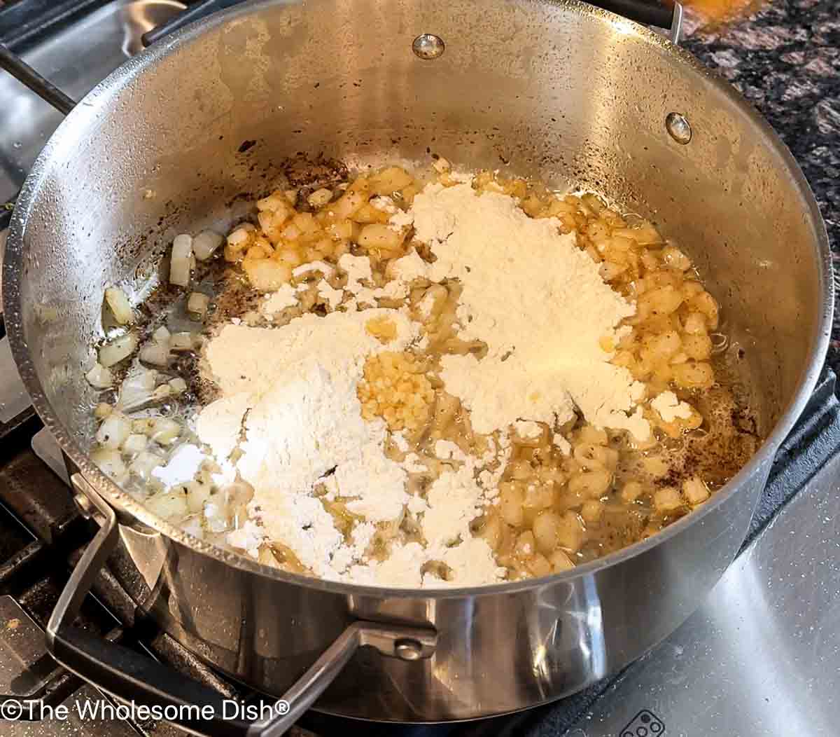 Adding flour and minced garlic to the pot.