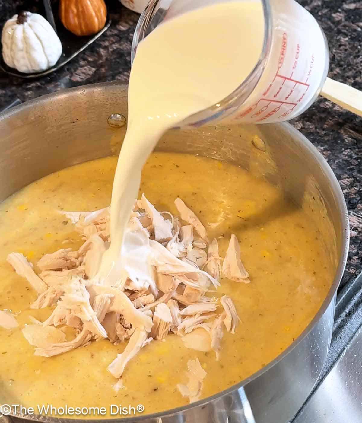 Adding shredded rotisserie chicken and half & half to the pot.