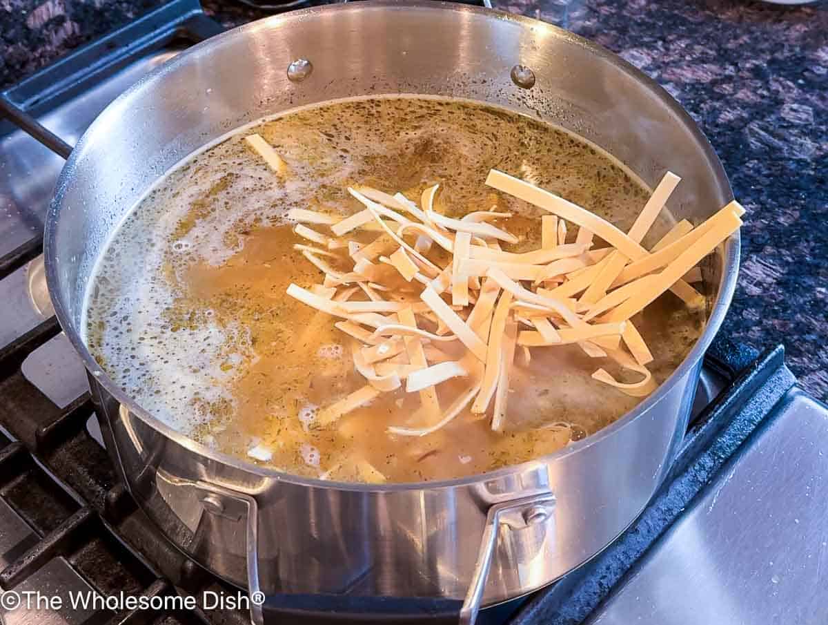 Adding egg noodles to the soup pot.