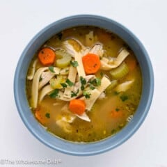 Blue bowl full of chicken noodle soup.