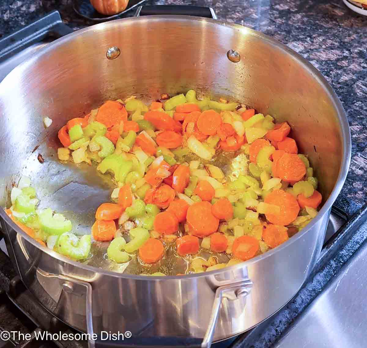 Carrots, celery, and onion sautéing in a large soup pot.