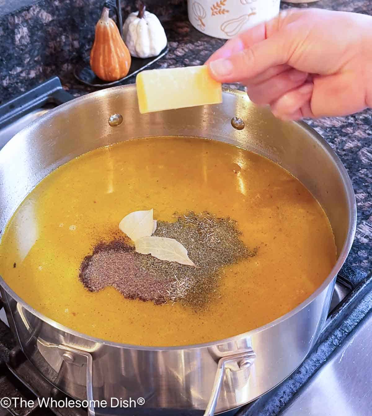 Adding seasoning and a parmesan cheese rind to the soup pot.