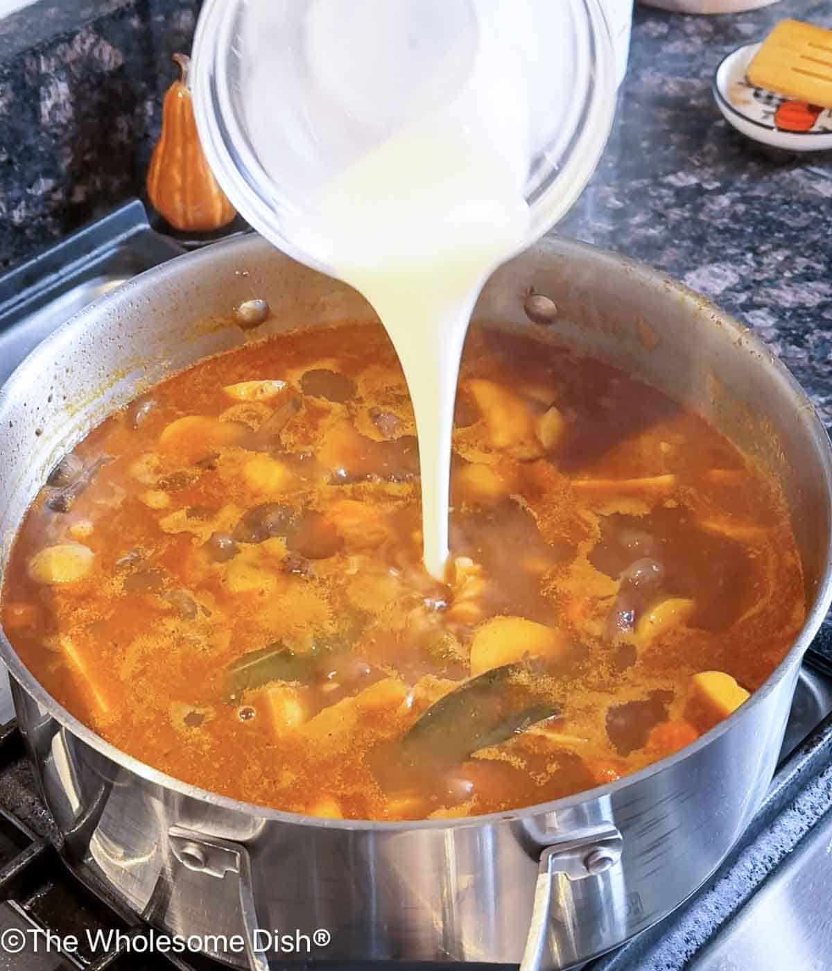 Adding a corn starch slurry to the soup.