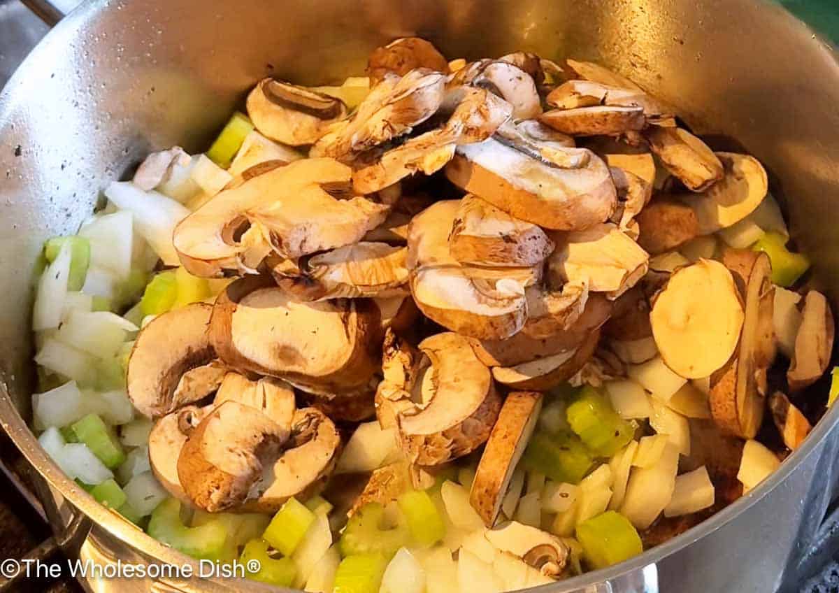 Onions, celery, and mushrooms sautéing in a soup pot.