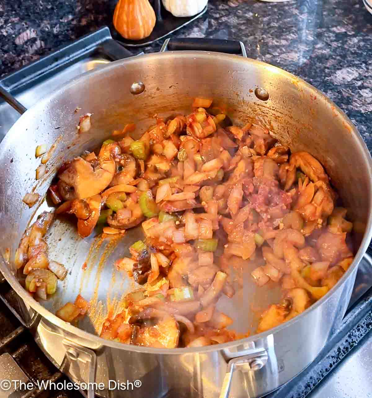 Tomato paste and garlic added to the sautéing veggies.