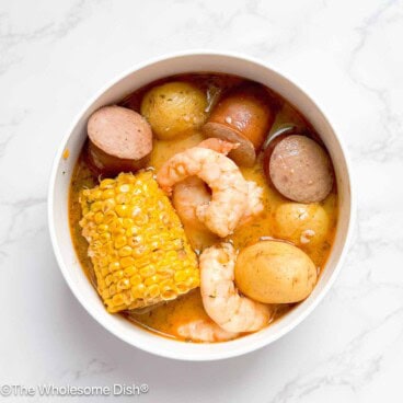 Bowl full of shrimp, potatoes, sausage, corn, and broth.