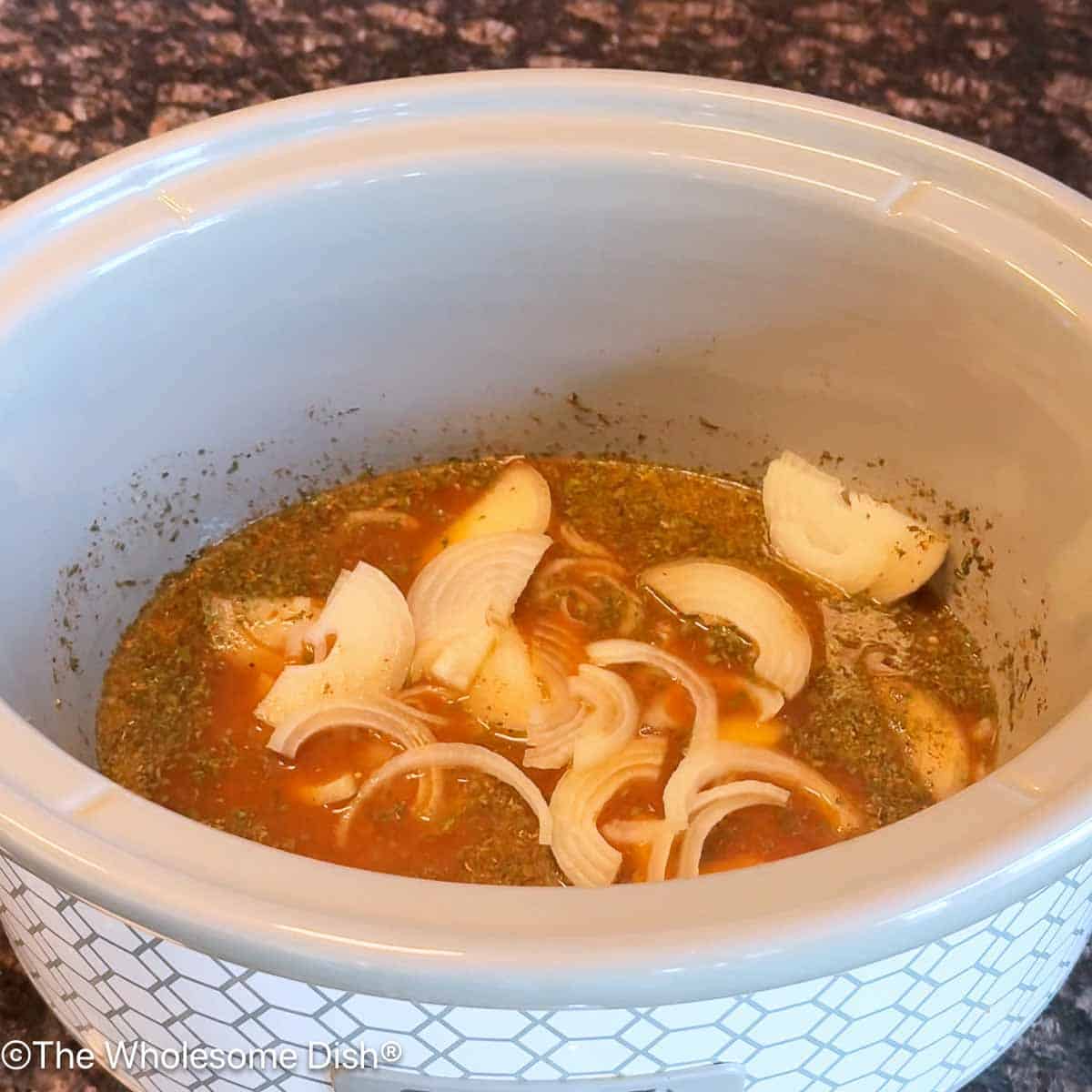 Adding sliced onion to the crock pot.