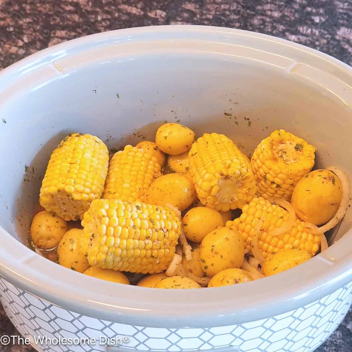 Baby potatoes and half ears of corn added to the crock pot.