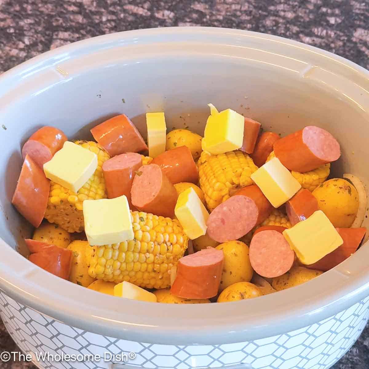 Sliced smoked sausage and butter added to the crock pot.